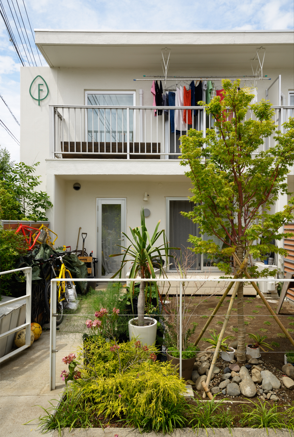 Modern two-storey white house with small garden, converted from East Japan Railway employee dormitory.
