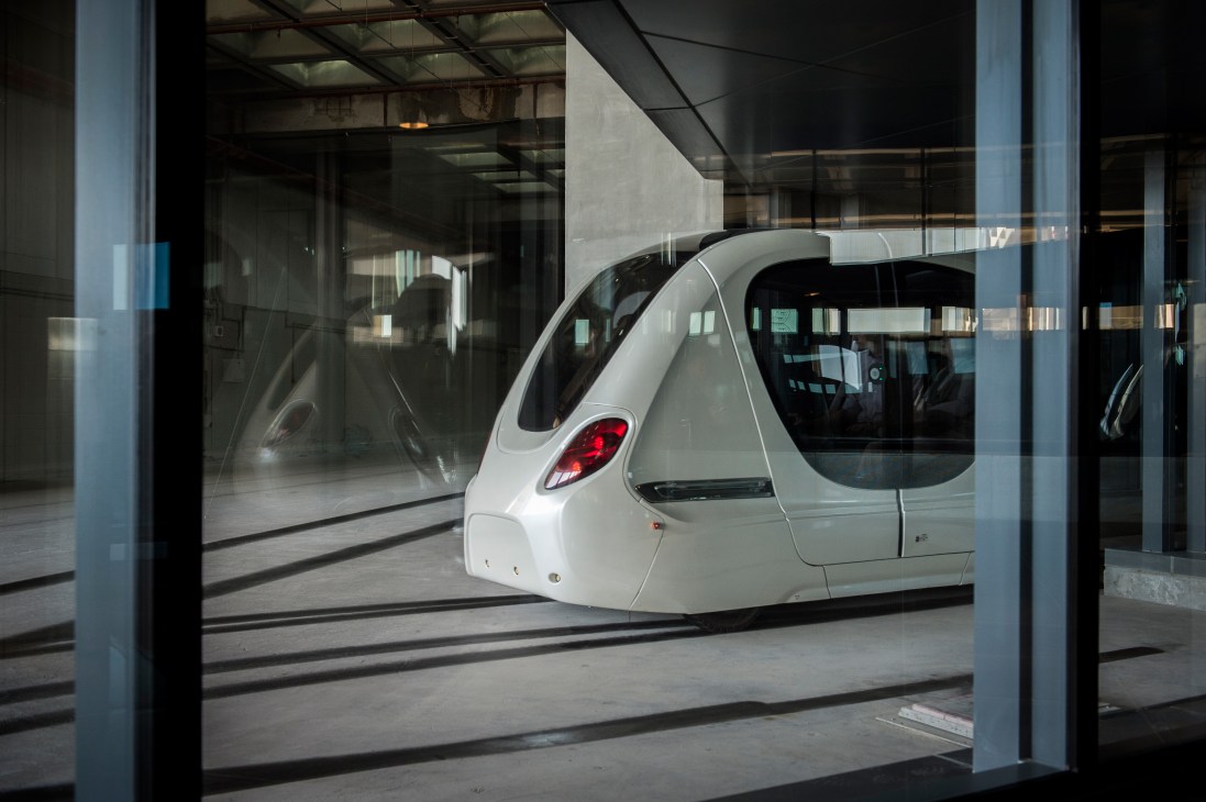 White driverless pod-shaped electric vehicle in underground transit station at Masdar City.