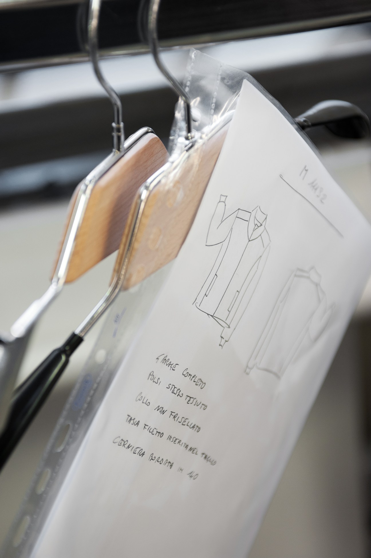 Garment sketches and fabric samples hanging on hangers during Armadillo Merino's design process.