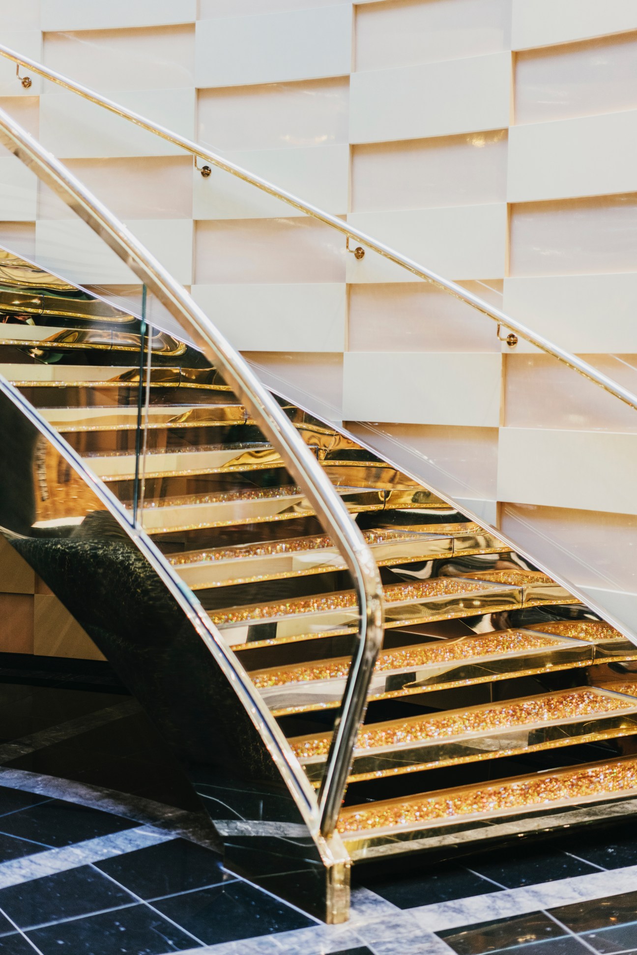 Illuminated staircase with white walls, gold-trimmed steps, and polished metal railings on MSC Preziosa.