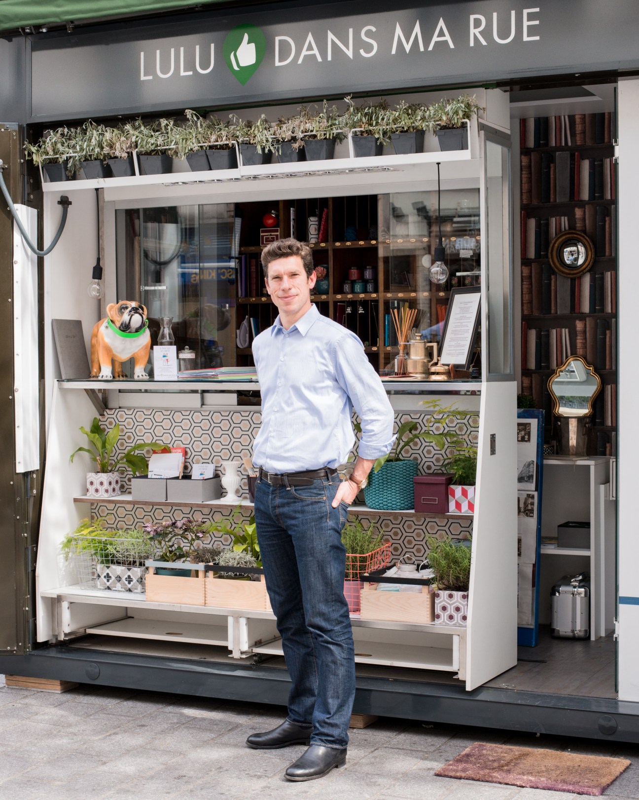 Charles Edouard Vincent standing in front of the Lulu Dans ma Rue kiosk storefront in Paris.