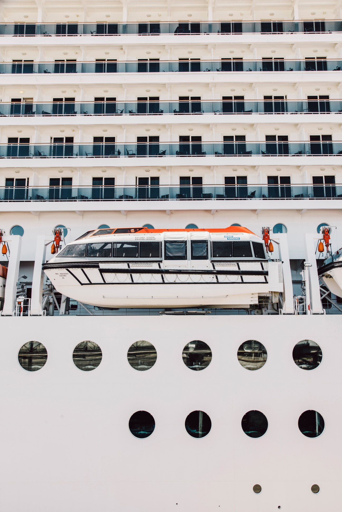 MSC Preziosa cruise ship lifeboat mounted on white hull with multiple cabin balconies above.