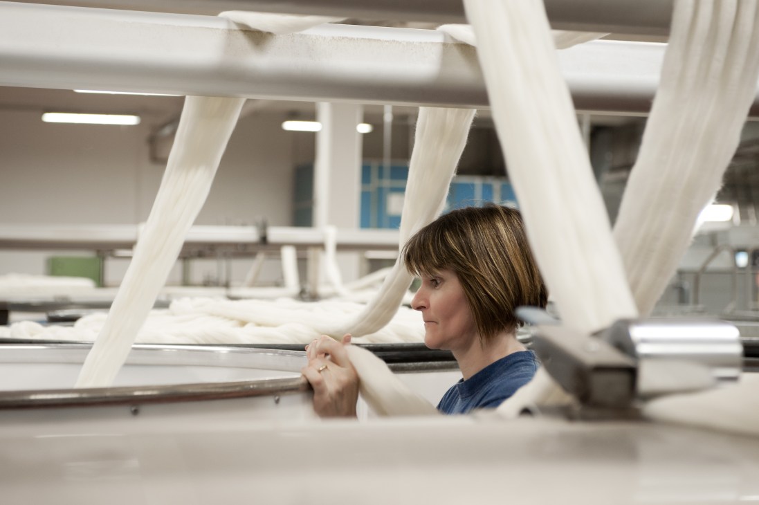 Worker combing wool fibers at Reda's textile mill in Biella, Italy.
