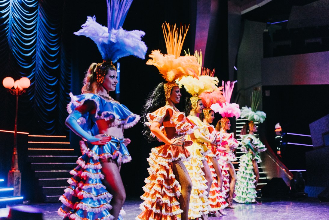 Dancers in colorful ruffled dresses perform on stage during MSC Preziosa's cruise entertainment show.