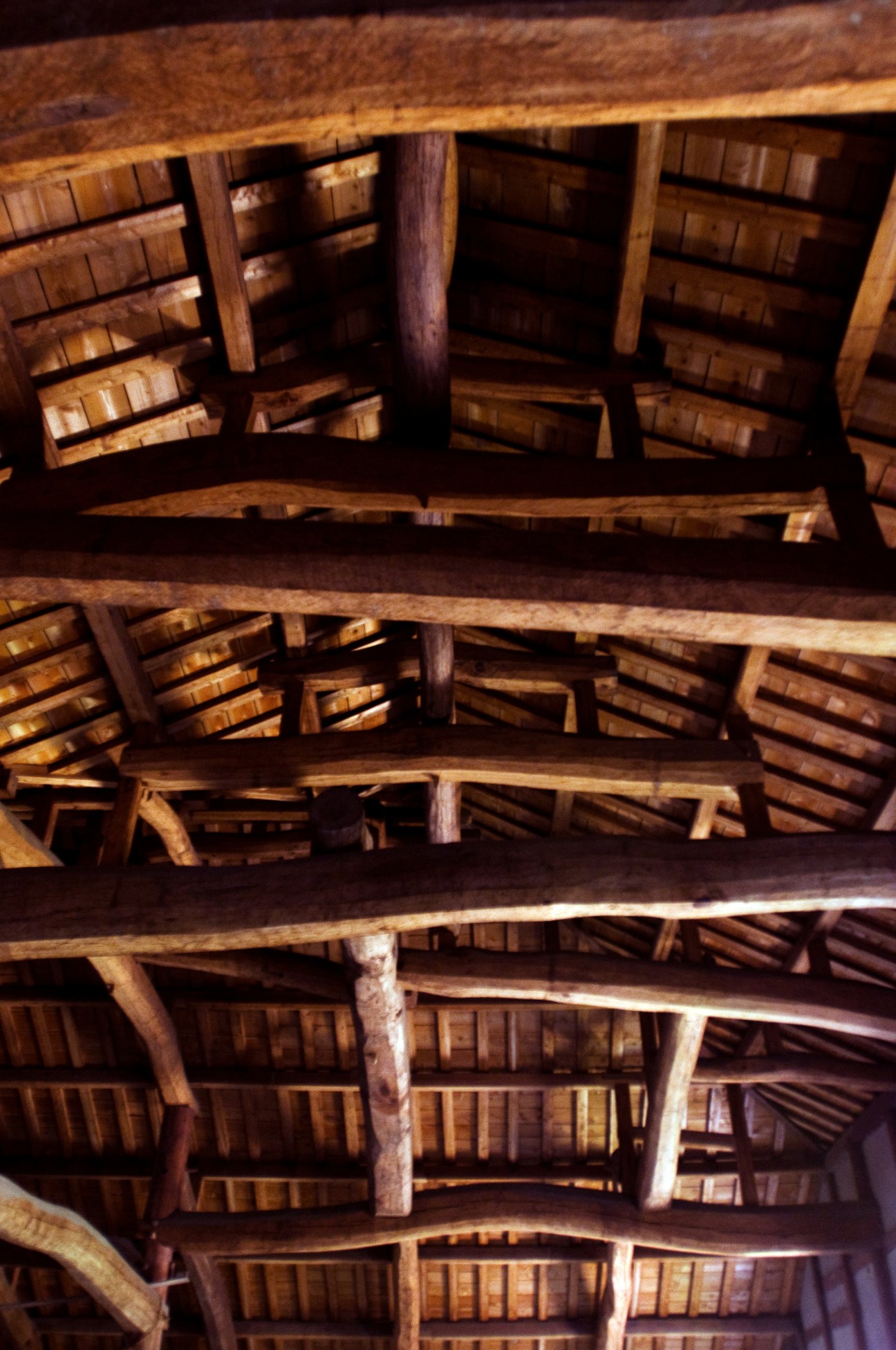 Interior view of wooden beams and rafters of a traditional Japanese structure showing intricate carpentry.