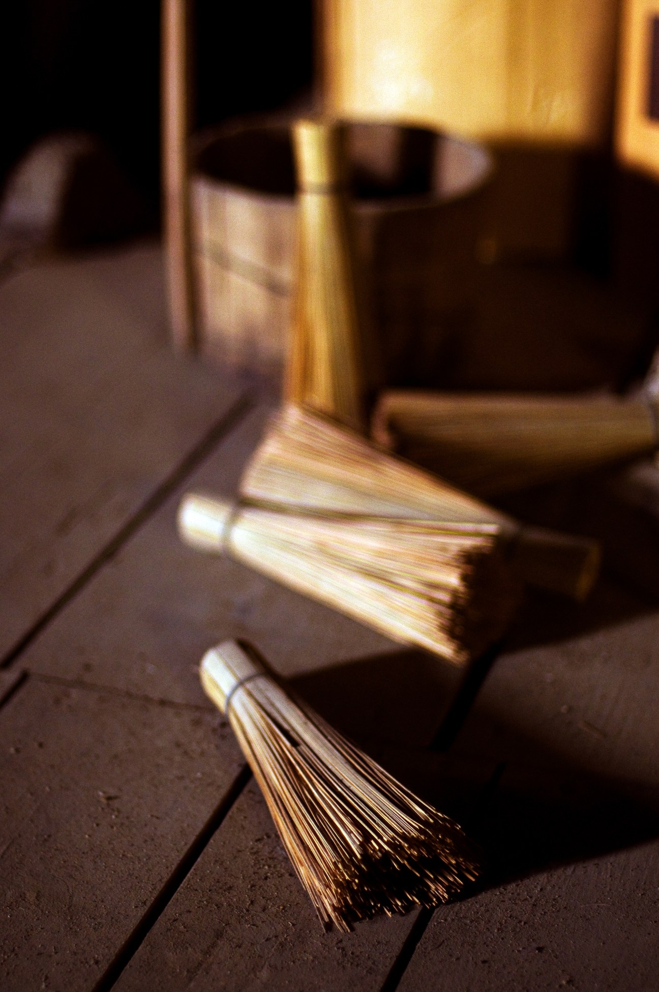 Wooden brushes with natural bristles lying on a dark wooden floor in warm light.