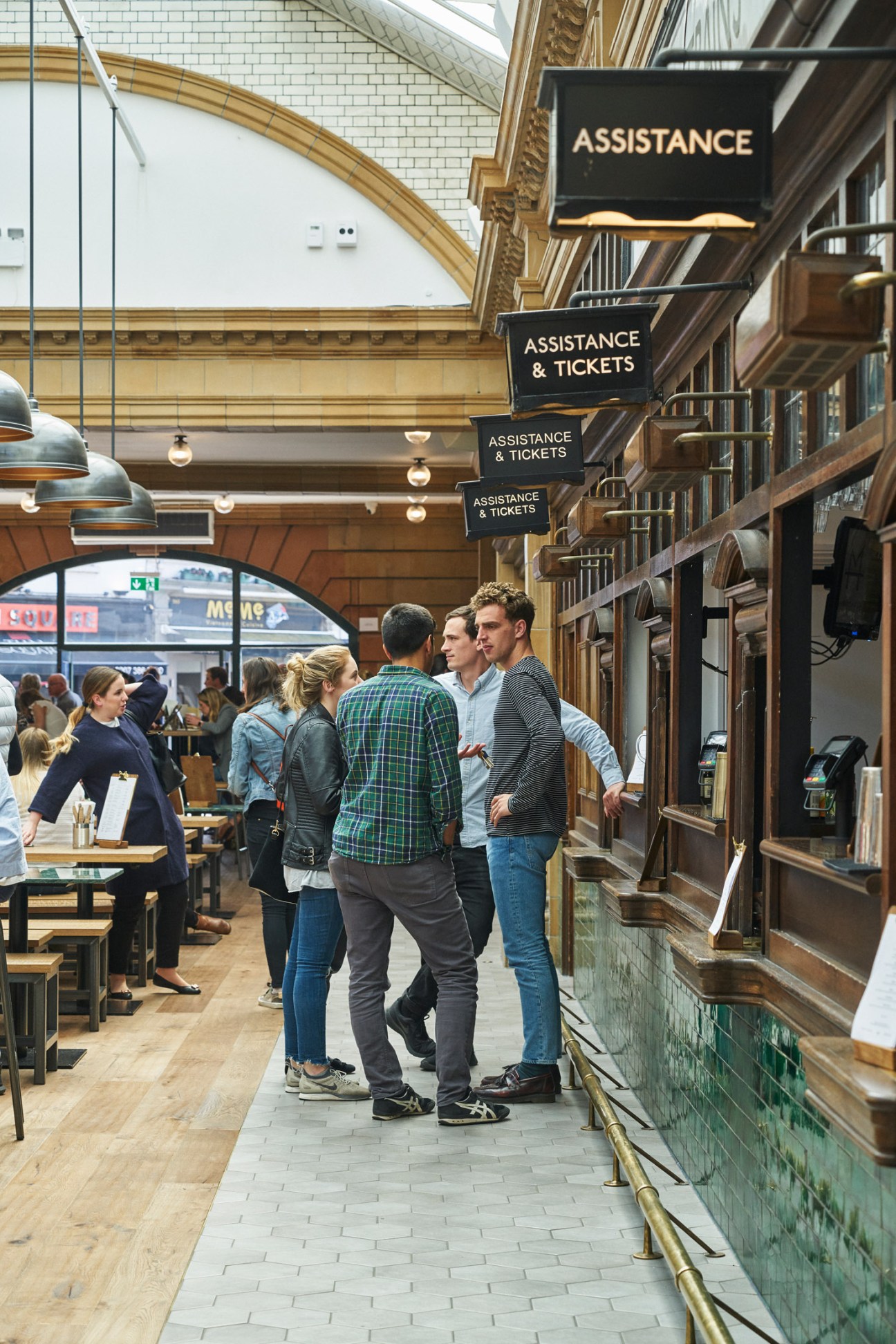 Interior of Market Hall Fulham showing restored Edwardian architecture with signage and people browsing food vendors.