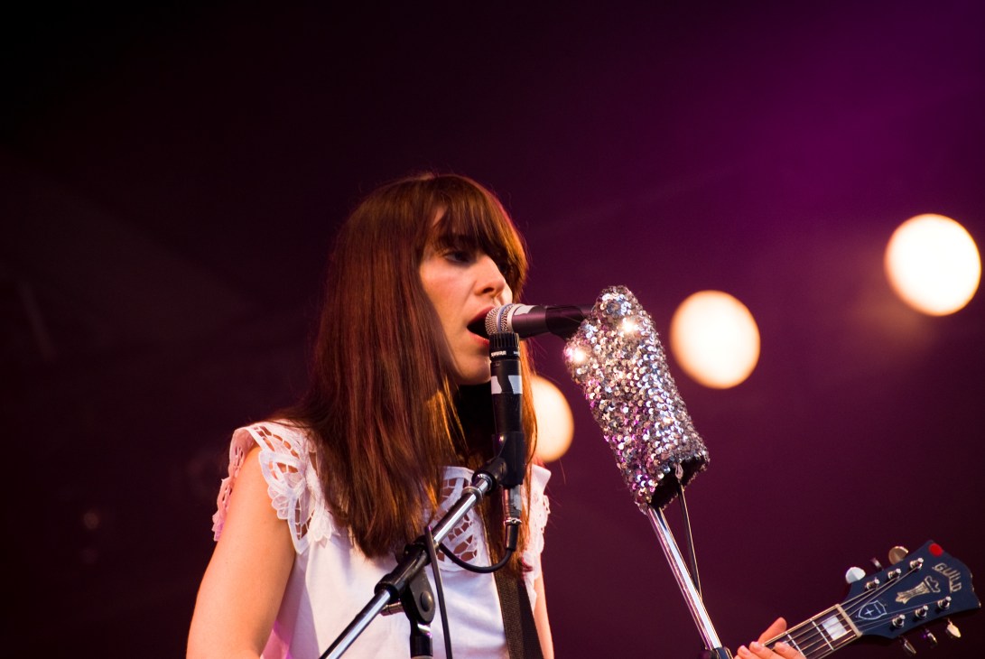 Feist performs at the Orange Court stage with a sequined microphone cover under stage lighting.