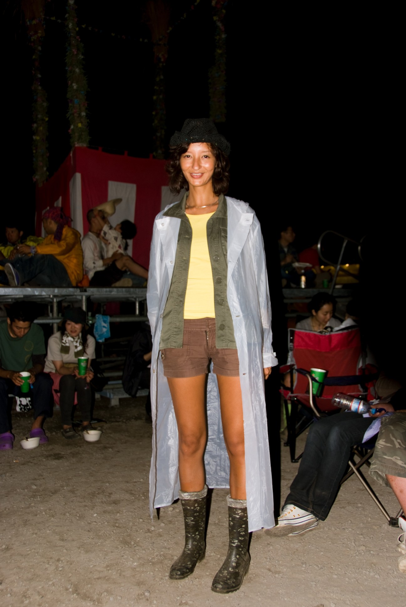 Woman wearing a long cardigan, yellow top, brown shorts and patterned boots at Fuji Rock festival campsite.