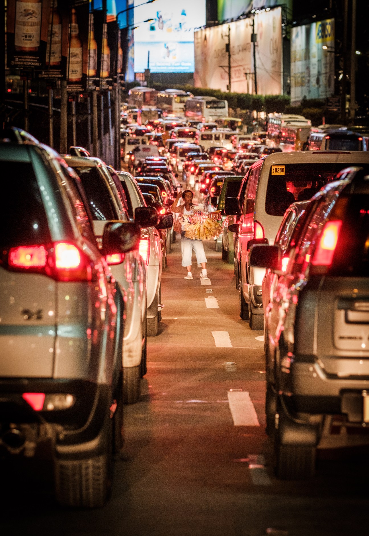 Heavy traffic congestion at night on Manila's EDSA mass-transit system with taxis and vehicles with brake lights illuminated.