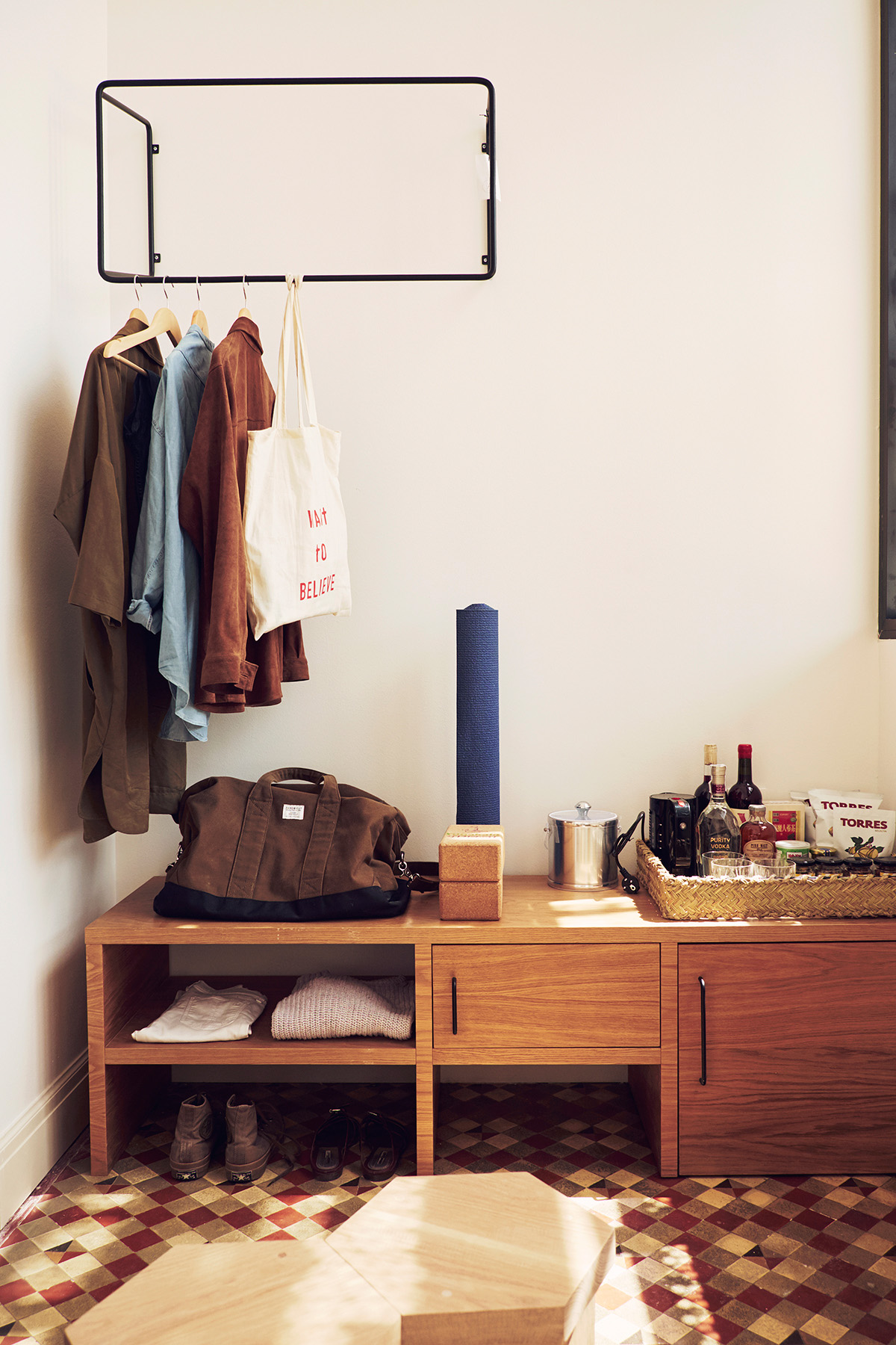 Hotel room detail with wooden storage unit, wall-mounted clothing rack, and minimalist decor at Casa Bonay.