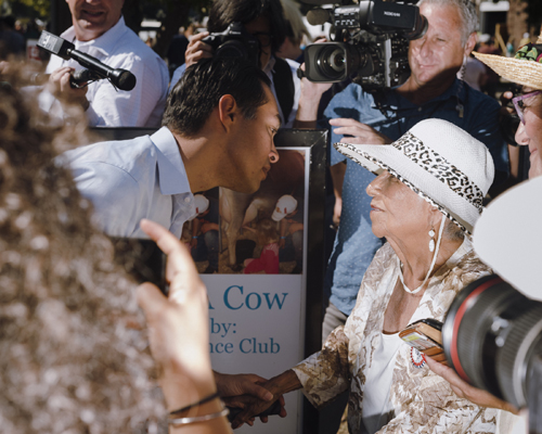Julián Castro waving to supporters at Iowa State Fair surrounded by media and crowd.