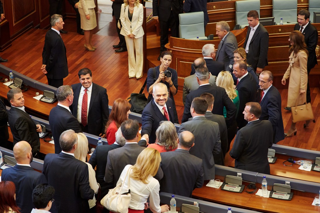 Edi Rama surrounded by officials and press in Kosovo's parliament chamber.