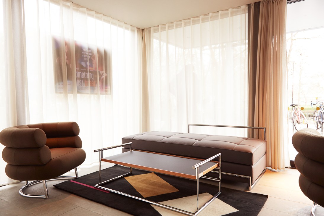 Brown Bibendum chairs in a modern living space with floor-to-ceiling windows and contemporary furniture.