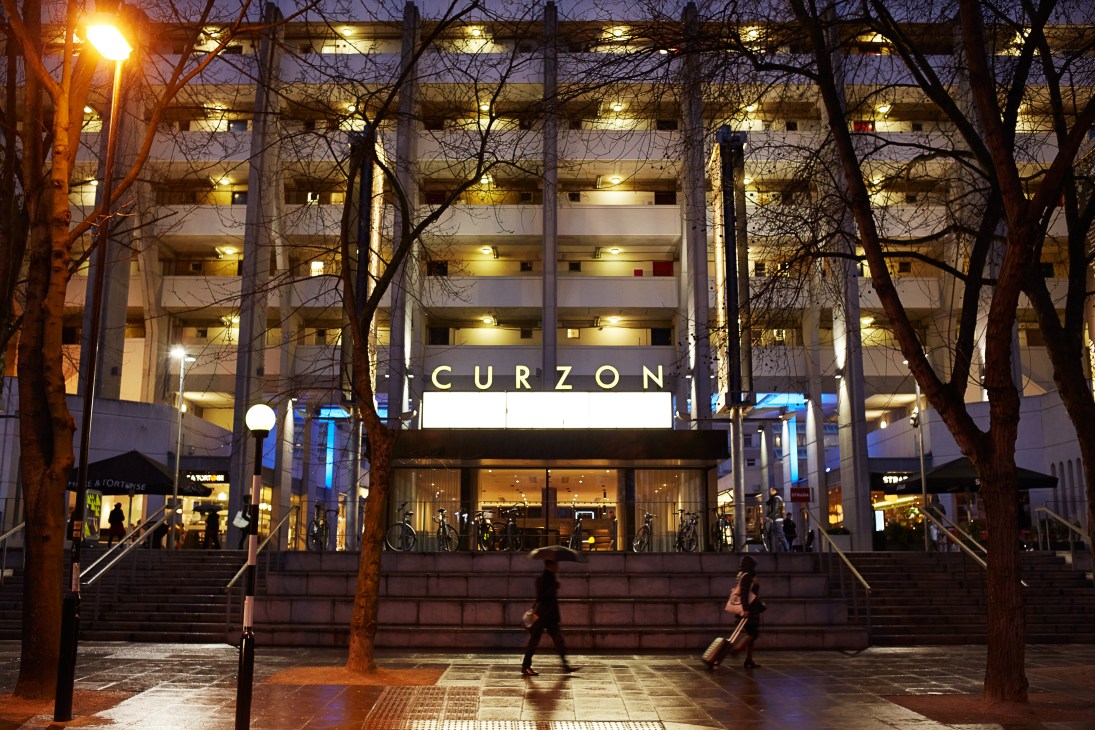 Curzon Bloomsbury cinema facade at night in the Brunswick Centre with illuminated signage and bare trees.