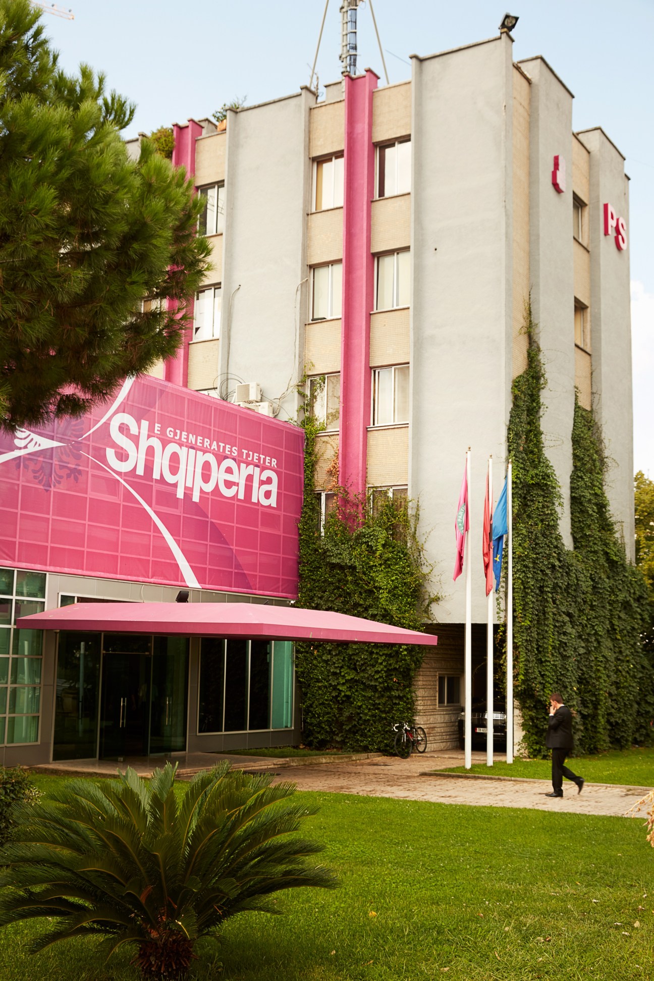 Socialist Party headquarters building in Tirana with pink vertical stripes and signage.