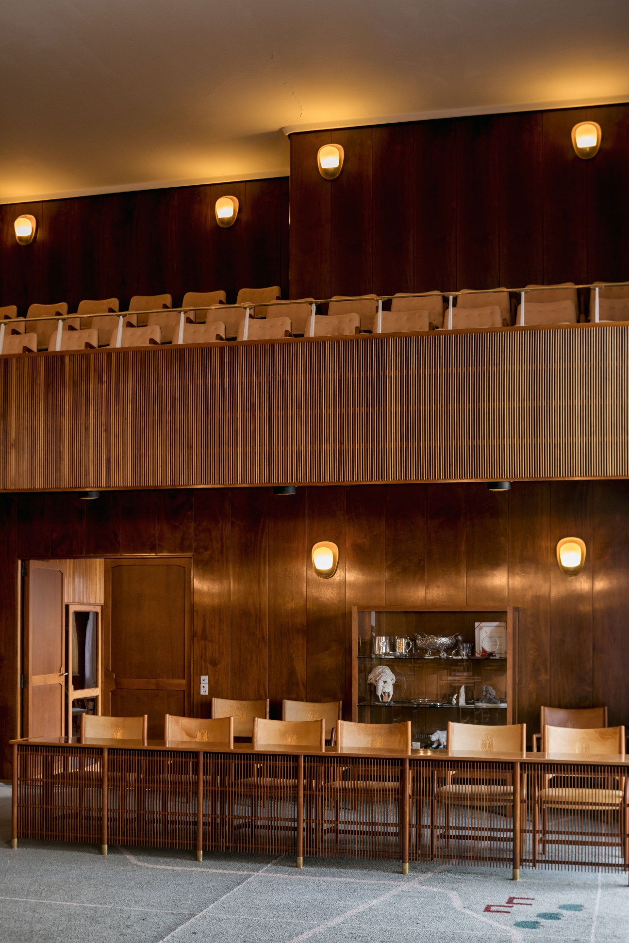 Aarhus city council chamber with tiered seating, dark wood paneling, and warm lighting fixtures.
