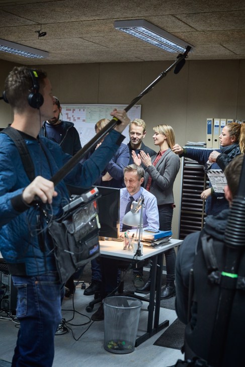 Film crew and cast members gather on set during production of Danish thriller Below the Surface.