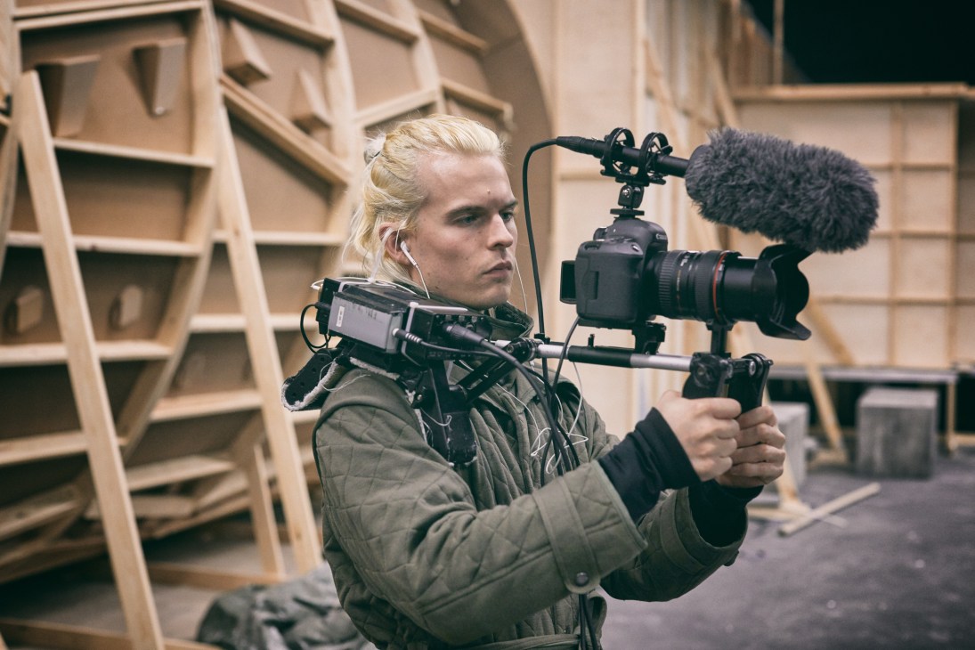 Camera operator Mathias Broe holds professional film camera equipment on a television set.