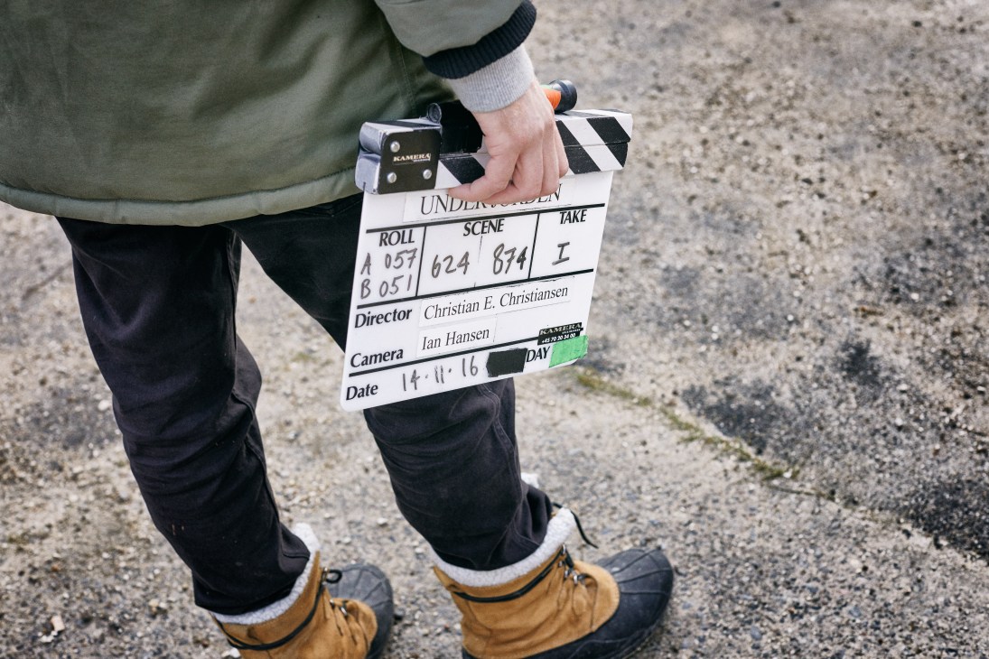 A crew member holds a film clapperboard for Below the Surface, showing scene and take numbers.