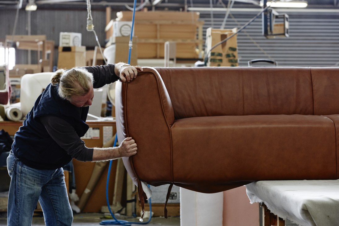A craftsperson upholsters a brown leather sofa in a Jardan factory in Melbourne.