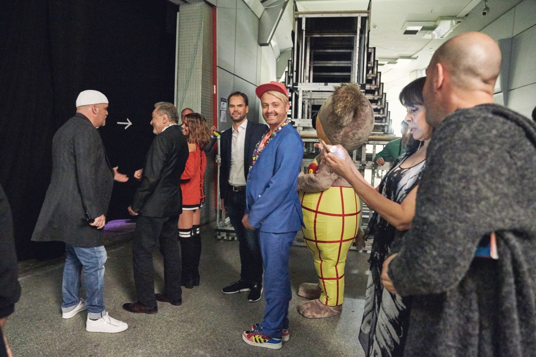 Ross Antony in blue suit standing next to a man-sized koala in yellow checked trousers backstage at Schlagerbooom.