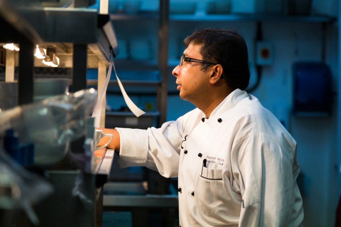 Executive chef Prahlad Hegde in white chef's coat monitoring kitchen service