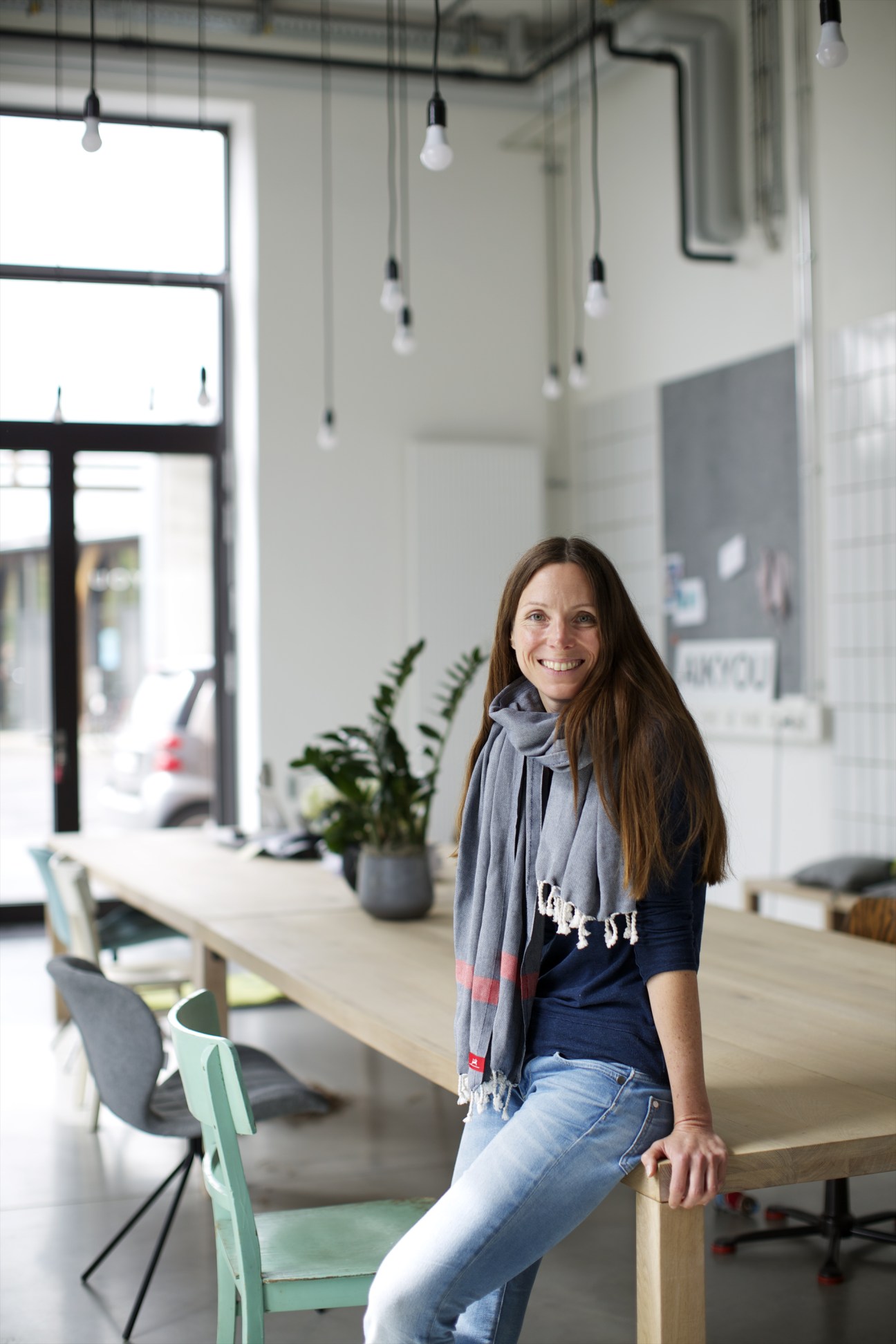Designer Bianca Renninger standing in a modern office space with pendant lights and large windows.