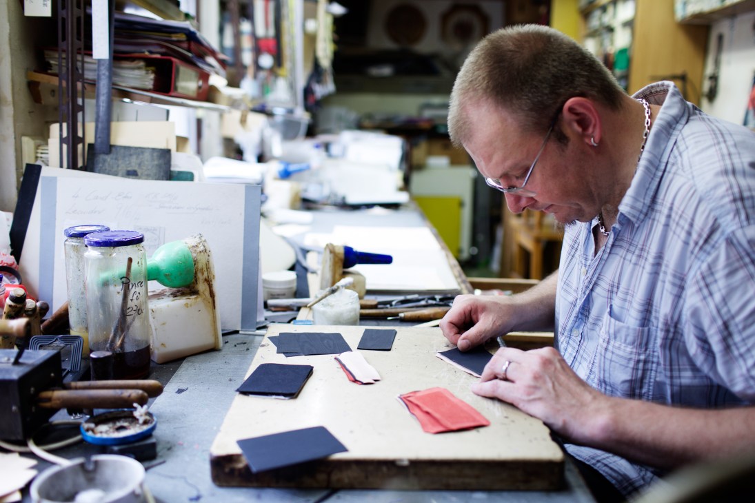 Leander Riedl at his workbench crafting leather goods in his Frankfurt studio workshop.