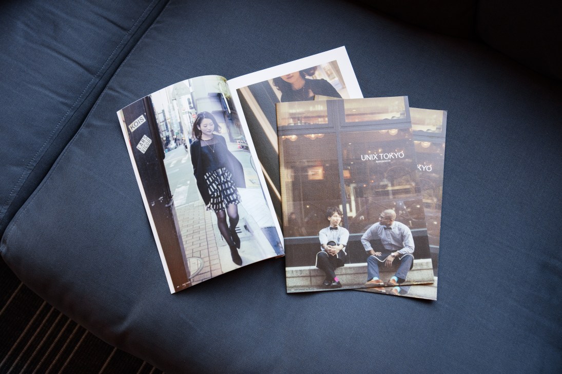Printed marketing materials for Unix Tokyo uniform company displayed on dark fabric.