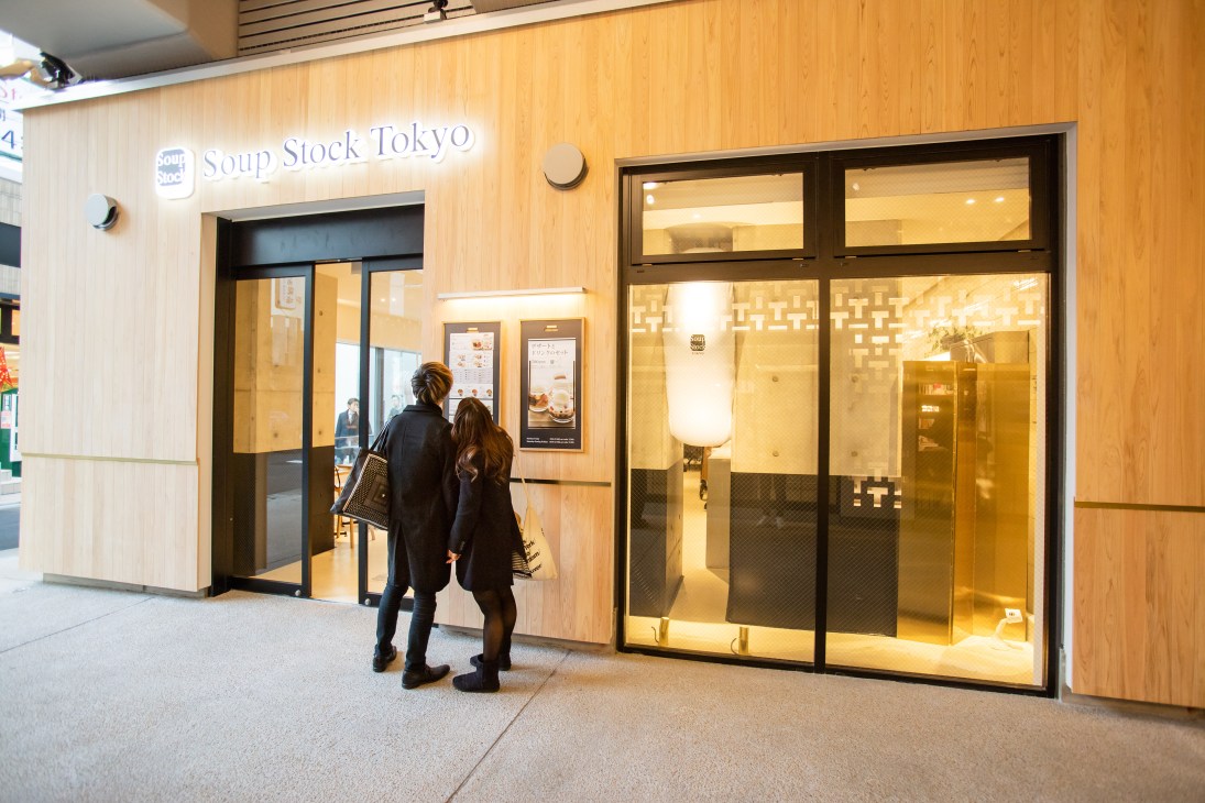 Soup Stock Tokyo storefront at Nakameguro Station with customers entering the modern wooden-facade restaurant.