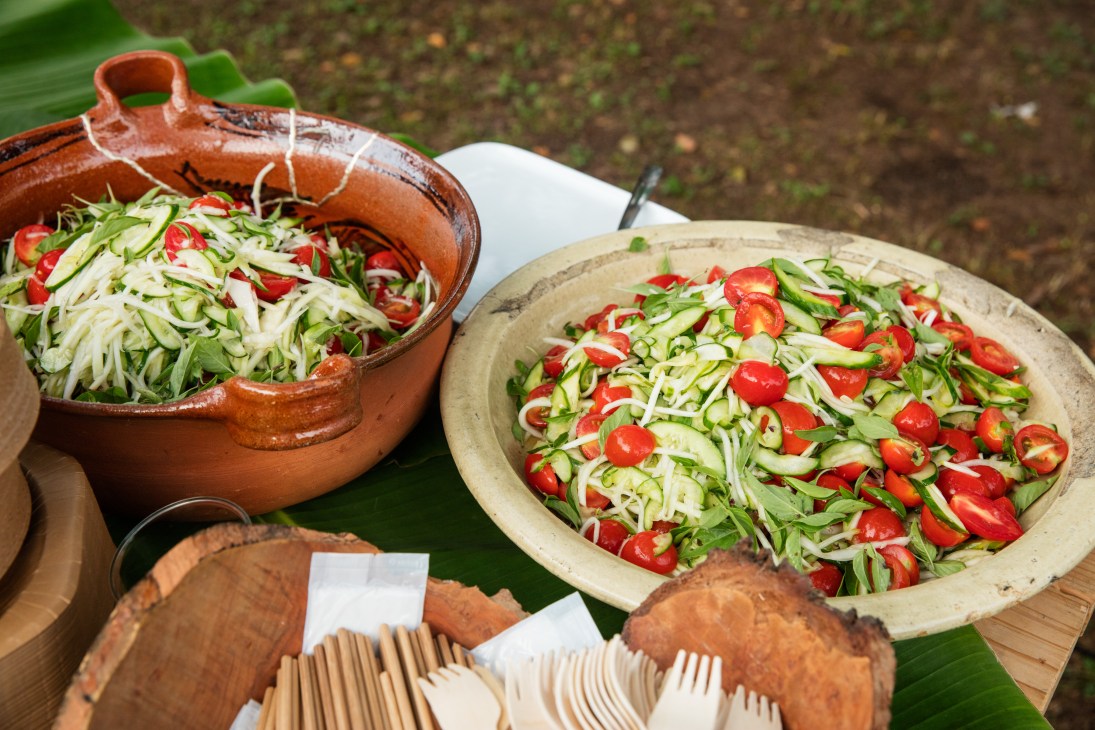 Fresh vegetable salads with cucumber, daikon, red chili peppers and herbs served in traditional ceramic bowls at an outdoor festival.