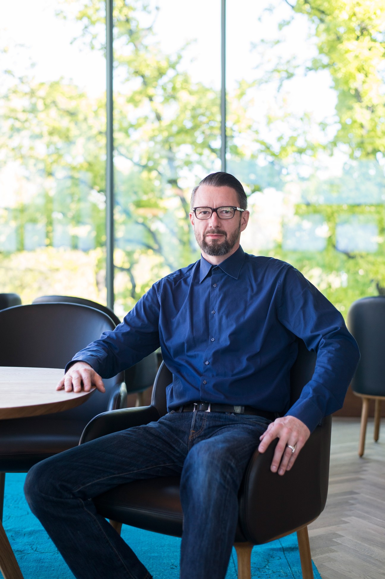 Robert Klanten, CEO of Gestalten, sits in a deep chair at the Gestalten Pavilion with views of Berlin's zoological garden behind him.