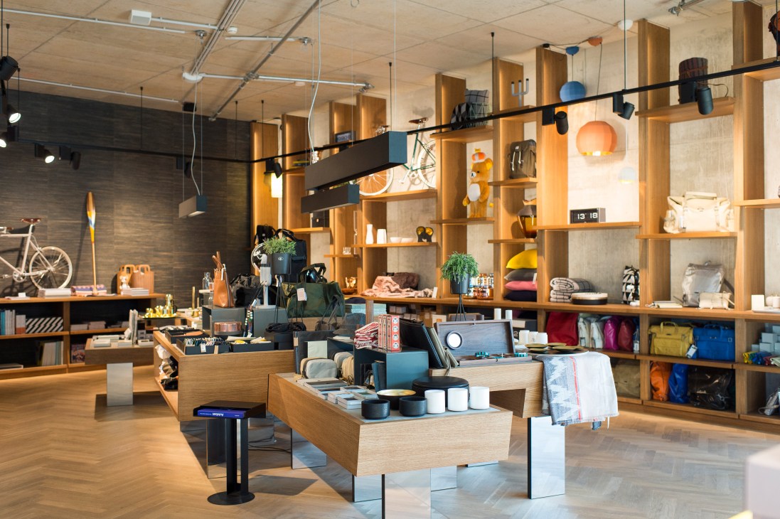 Interior of the Gestalten Pavilion with wooden shelving, design products, and minimalist furnishings.