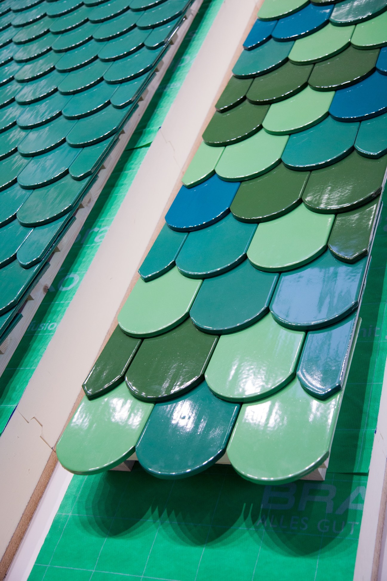 Colorful roof tile samples displayed in green, blue, and teal shades at the BAU construction fair.