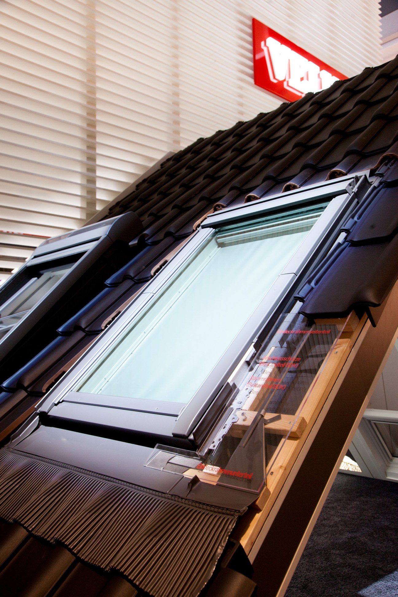Roof-mounted skylights with white frames installed on black tiles beneath a red neon sign.