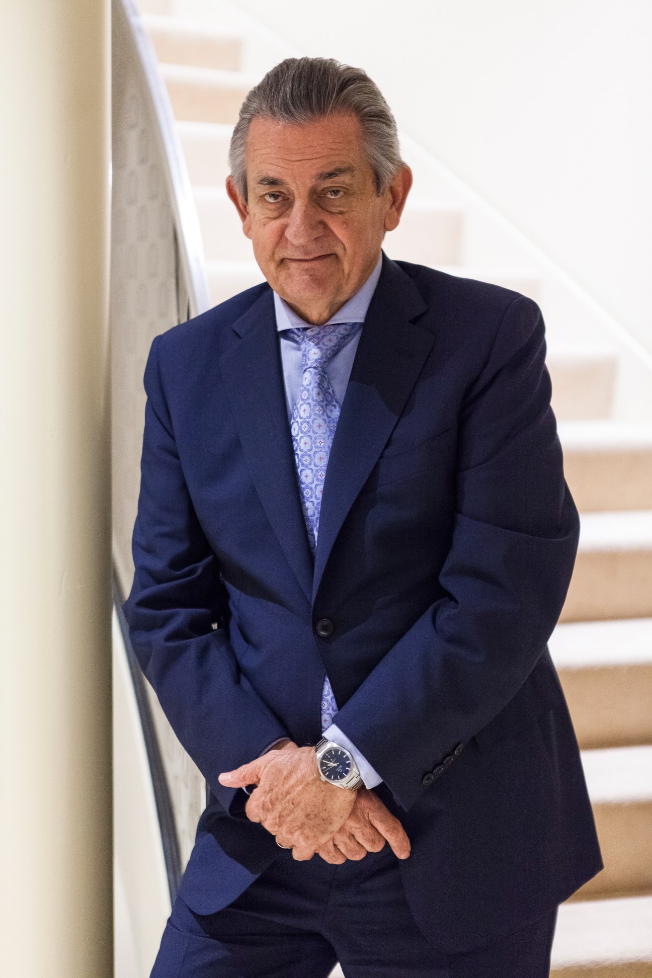 Omega president Stephen Urquhart in navy blazer and patterned tie standing on stairs