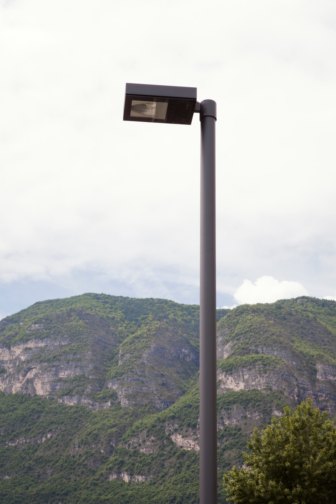 Ewo's FL light fixture mounted on a tall pole with mountainous landscape in background.