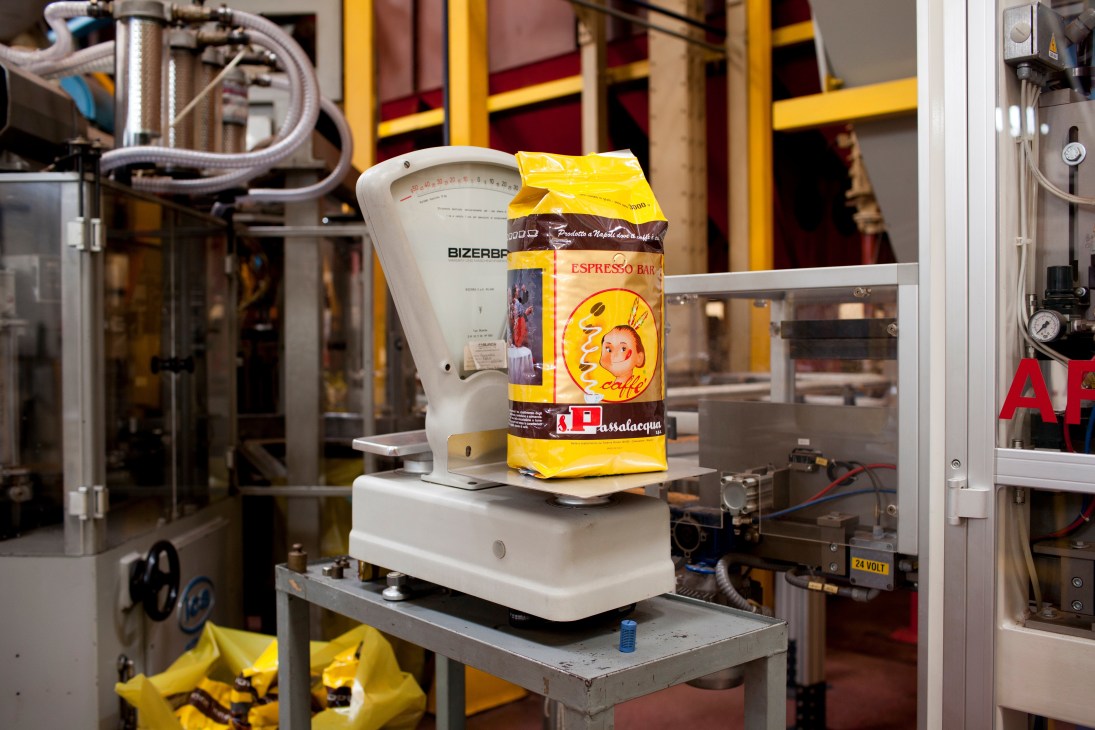A Passalacqua espresso coffee bag next to a vintage Bizerba scale in a roastery production facility.