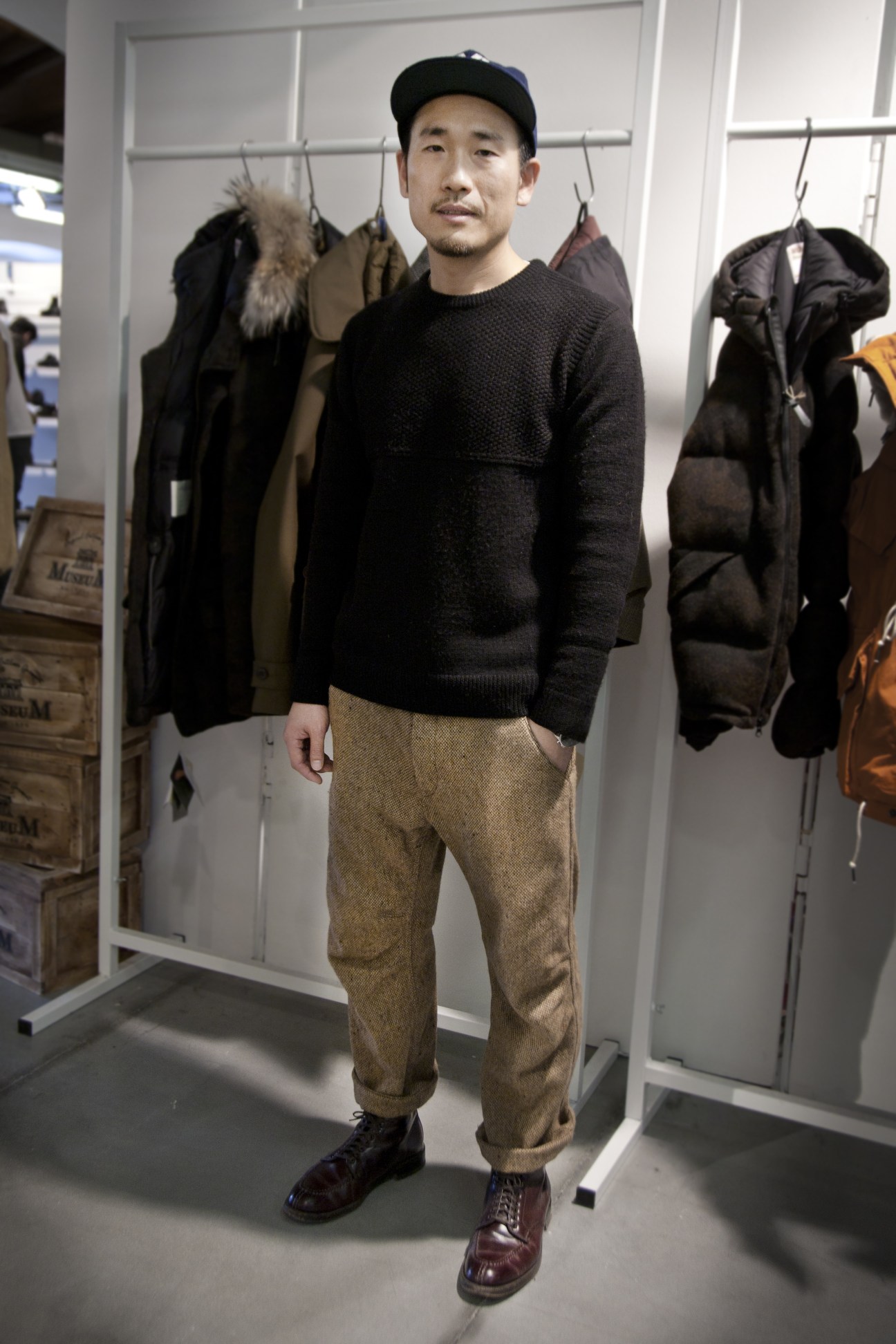 Cho Sung Jun, creative director of Italian outerwear brand Museum, stands at a booth displaying jackets and outerwear.