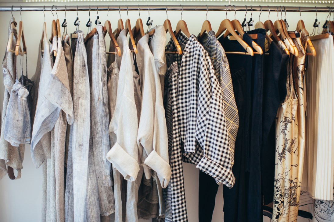 Wooden hangers display an array of clothing in neutral and patterned fabrics at Timi Hayek's boutique.