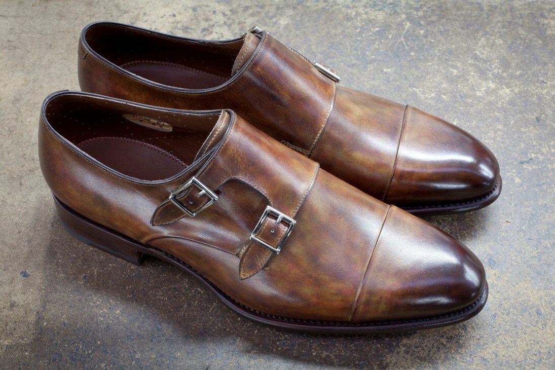 Pair of brown leather Santoni double monk shoes with buckle straps in calfskin.