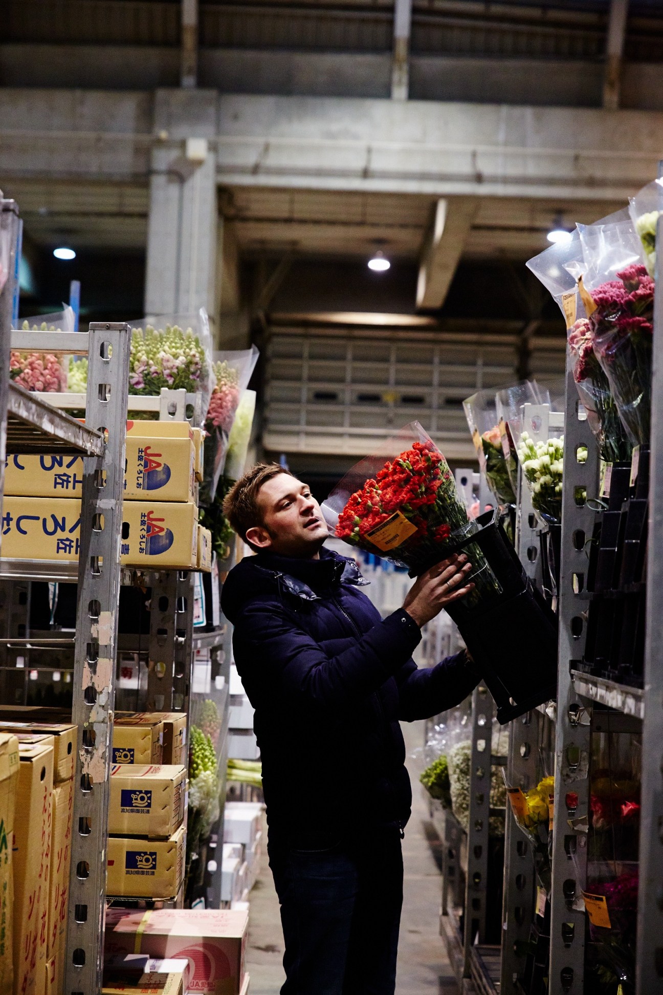 Nicolai Bergmann examines red carnations among flower displays at Ota market.