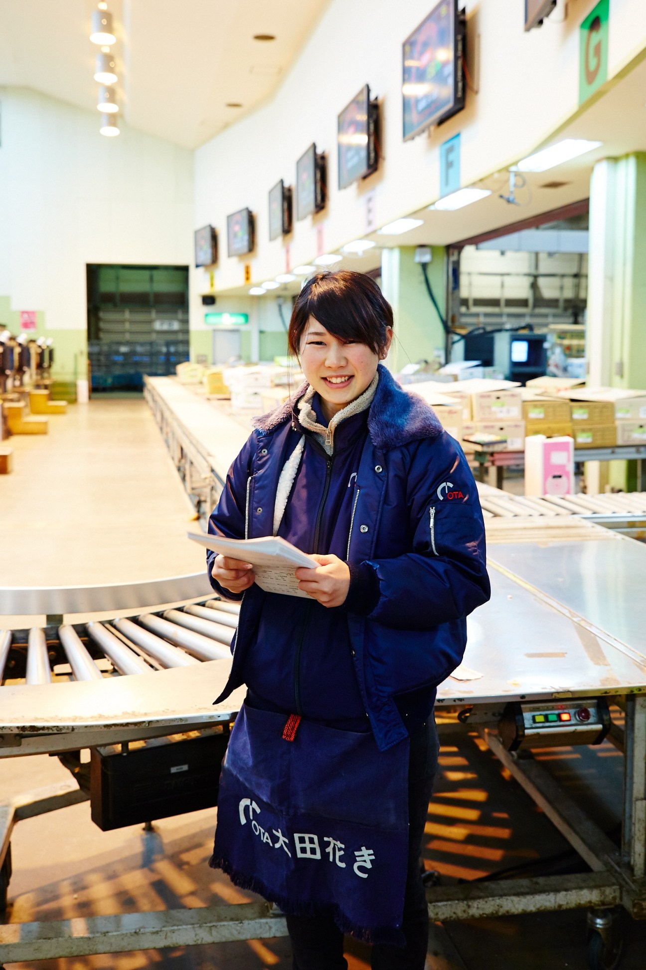 Mina Yoda from the Ota Floriculture Auction holds a clipboard in the flower market distribution center.