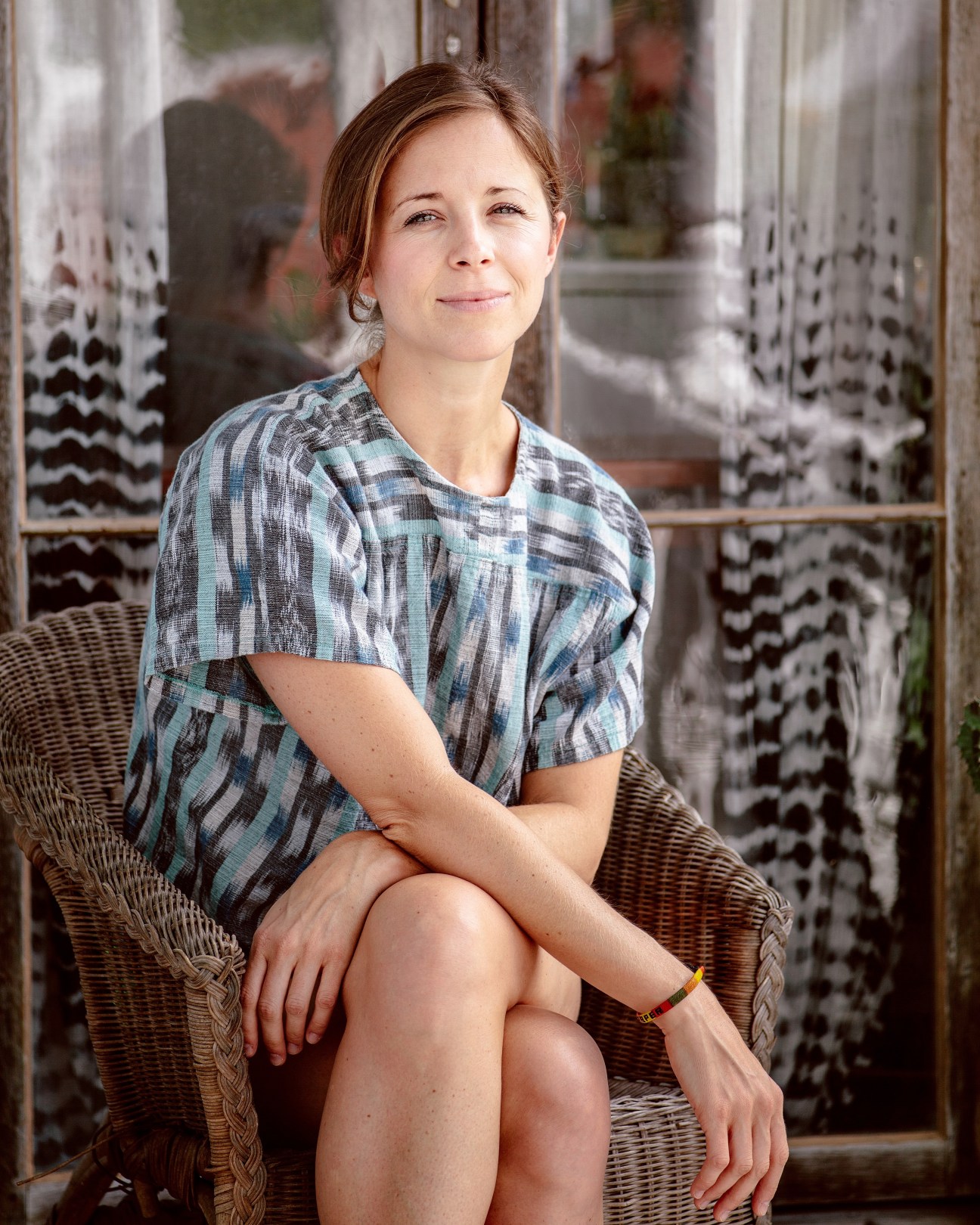 Harper Poe of Proud Mary Textiles sits on a wicker chair on a Charleston home piazza.