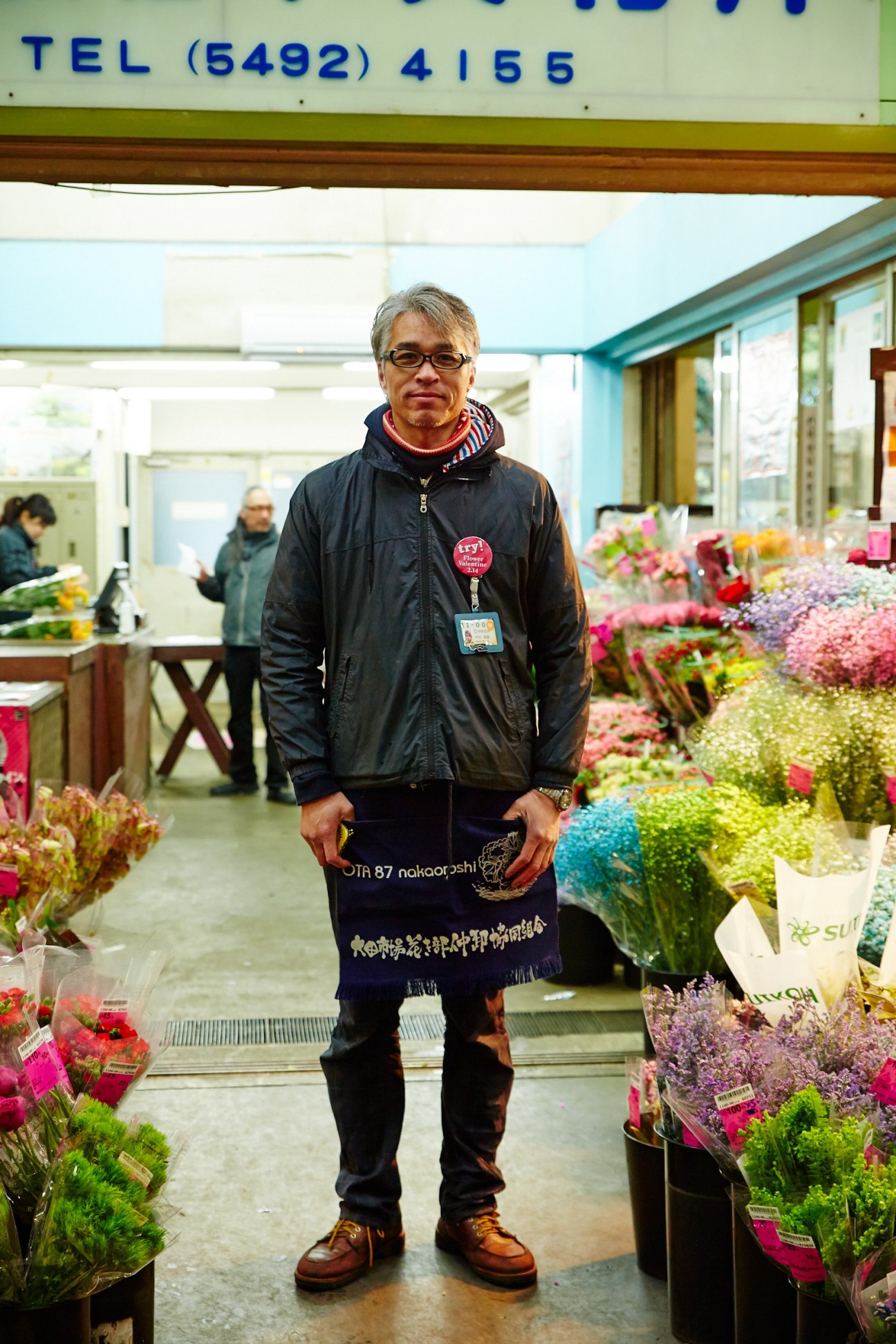 Takatoshi Nakaya, sales manager at Chuo Kaki wholesaler, stands among colorful flower buckets at Ota flower market.