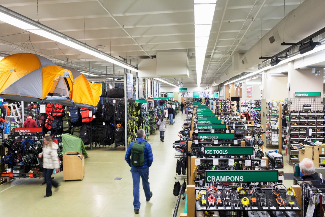 Interior of Mountain Equipment Co-op Vancouver store showing outdoor gear displays and customers shopping.