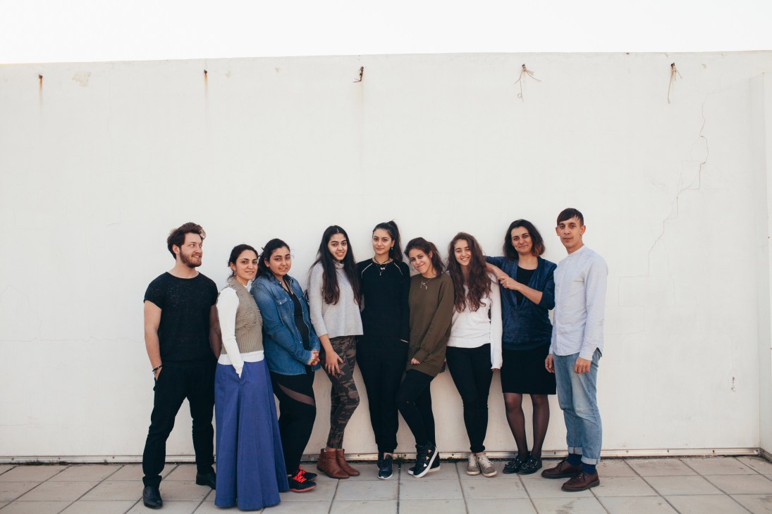 Nine students and staff members stand together against a white wall at Alba's fashion school in Beirut.