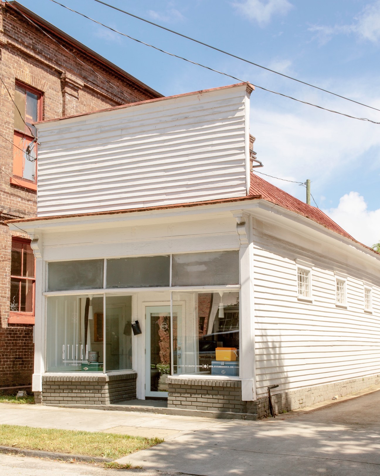 Modern storefront with white trim and large windows attached to a brick building on Cannon Street.