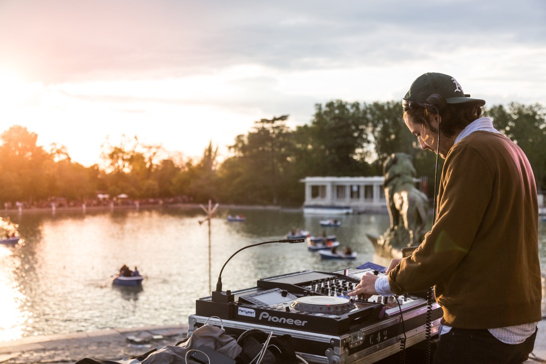 DJ Pascal Moscheni performs at a Pioneer turntable overlooking Buen Retiro Park at sunset during Madrid's San Isidro celebrations.